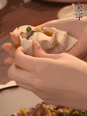 取一大勺餡料放進(jìn)餃子皮里，用大拇指按住頂部餡料，再用虎口掐出形狀。