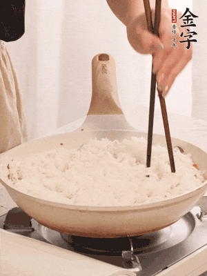 把瀝干水分的米飯均勻鋪在上面，筷子戳幾個(gè)洞，以便透氣，轉(zhuǎn)小火蓋上蓋子燜至水分收干，大概10分鐘。