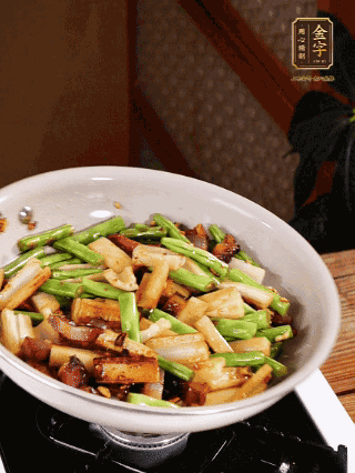 油熱下蒜末、干辣椒、醬肉煸炒出香味，依次下藕條、豆角翻炒均勻